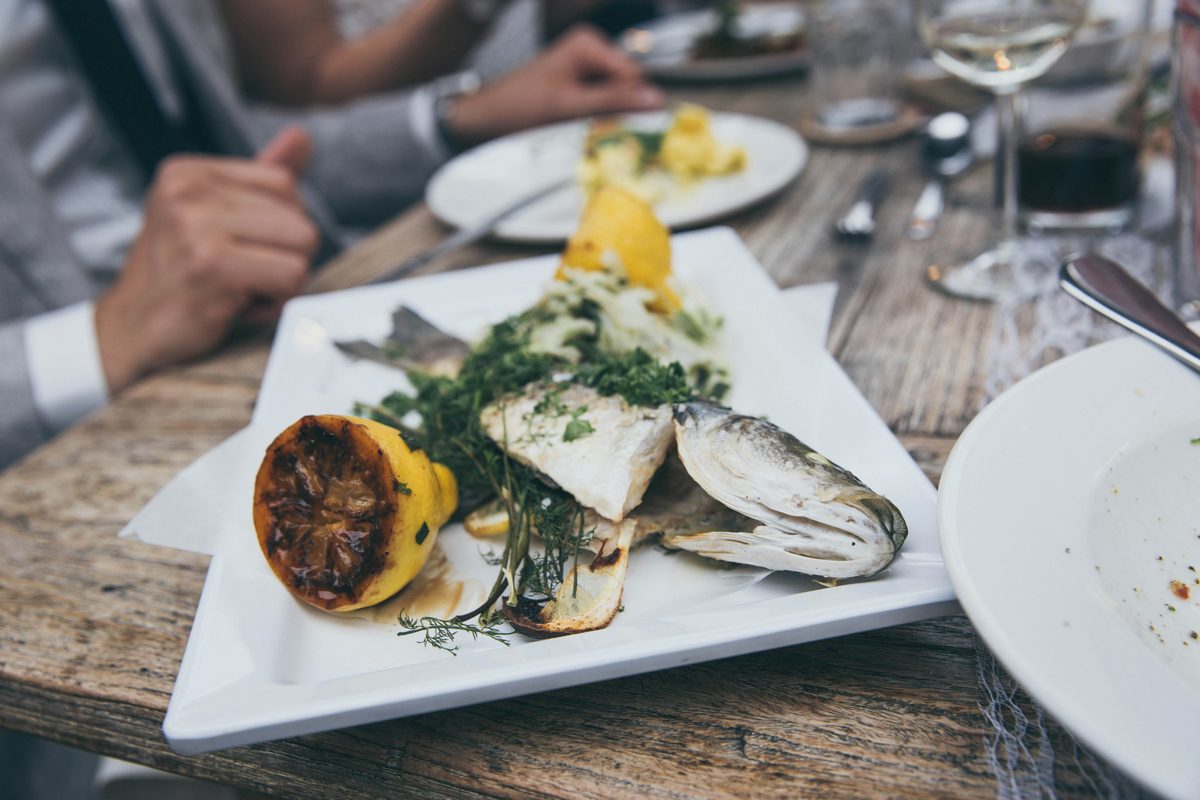 Et glas frisk hvidvin ved siden af en tallerken med grillet fish and shellfish