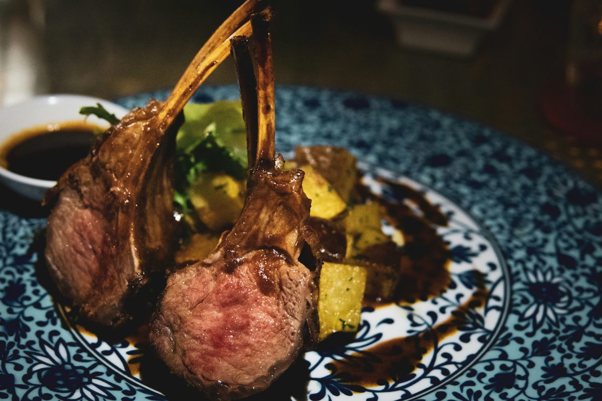 Et glas rødvin ved siden af en ovnstegt leg of lamb med rosmarin og hvidløg