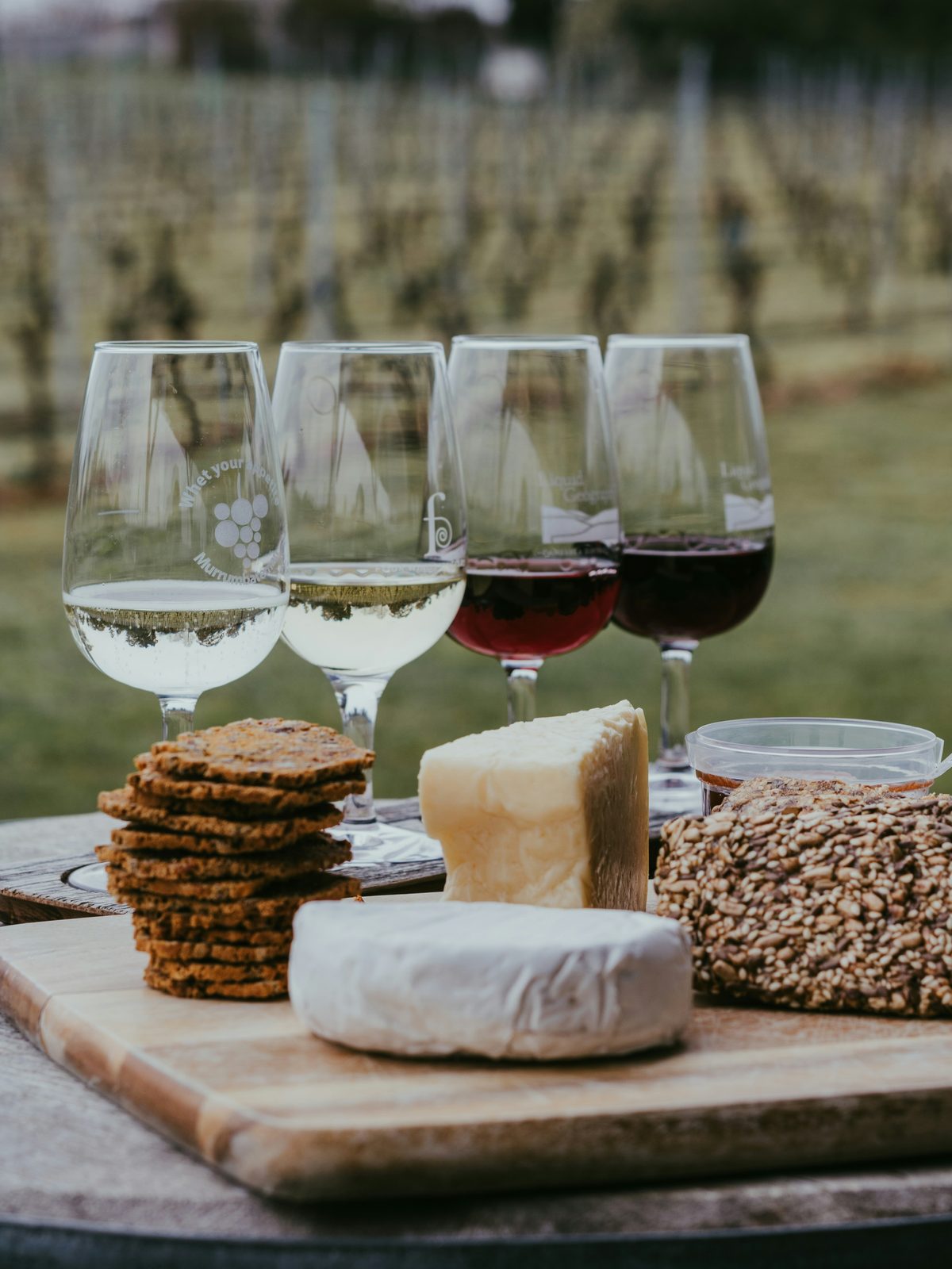 Ostebord med forskellige ostetyper, druer og et glas vin