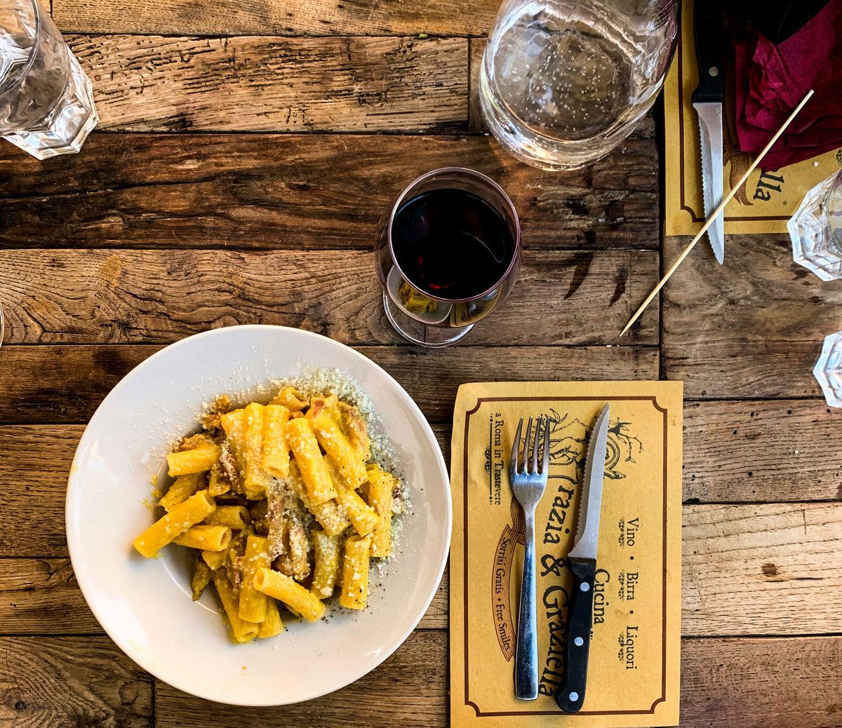 Et glas italiensk rødvin ved siden af en tallerken spaghetti bolognese